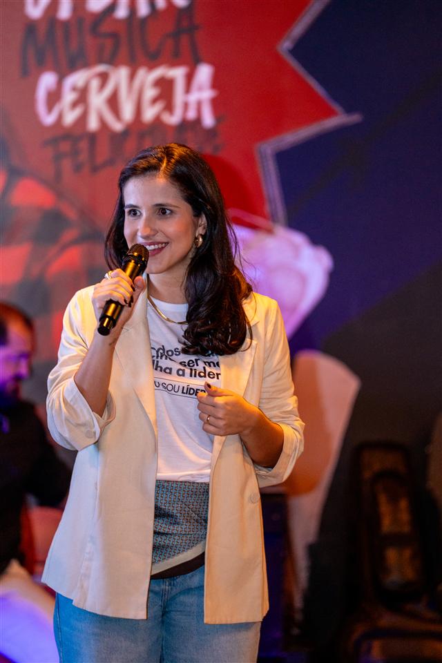 Allana Mansur discursando ao microfone em um evento ao vivo